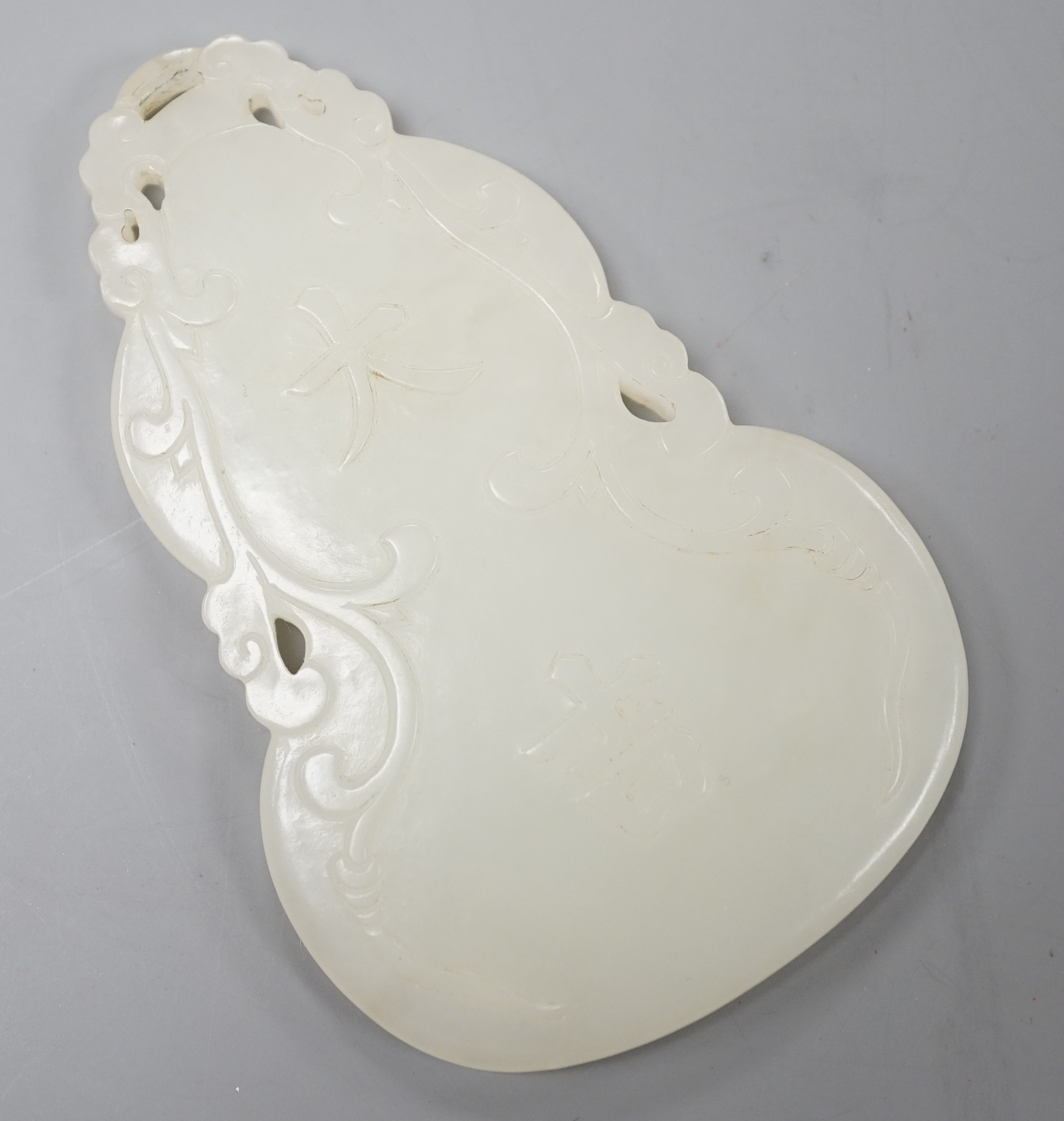 A Chinese inscribed white jade gourd shaped plaque on stand, with calligraphy, 12cms high.